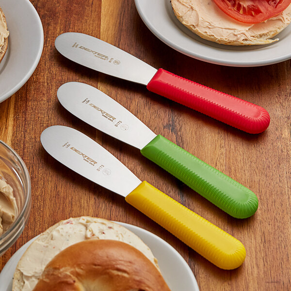 A group of Dexter-Russell sandwich spreaders with red, yellow, and green handles.