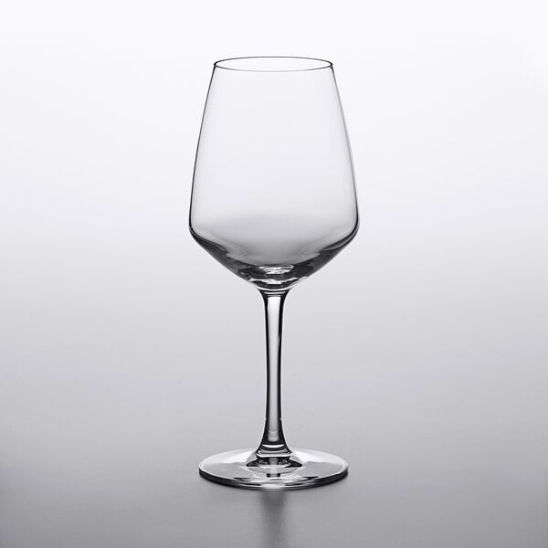 An empty Arcoroc wine glass on a white surface.