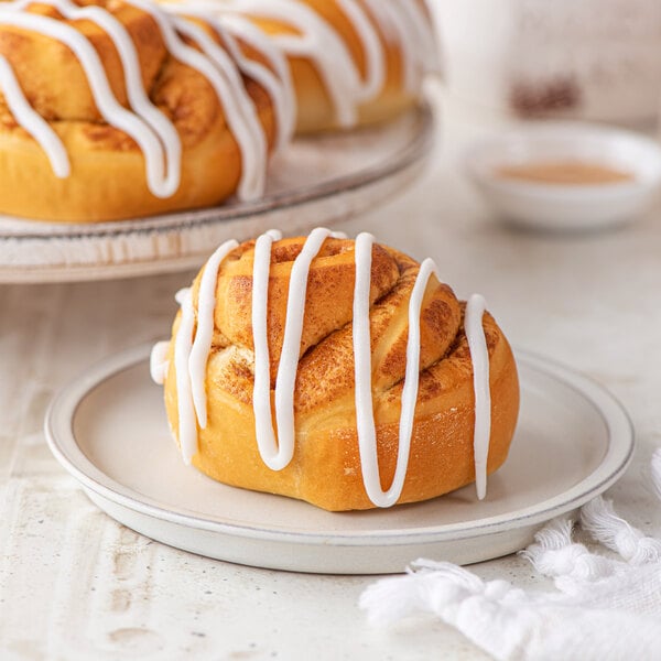 Unbaked Rich's Traditional Cinnamon Roll Dough with icing on a plate.