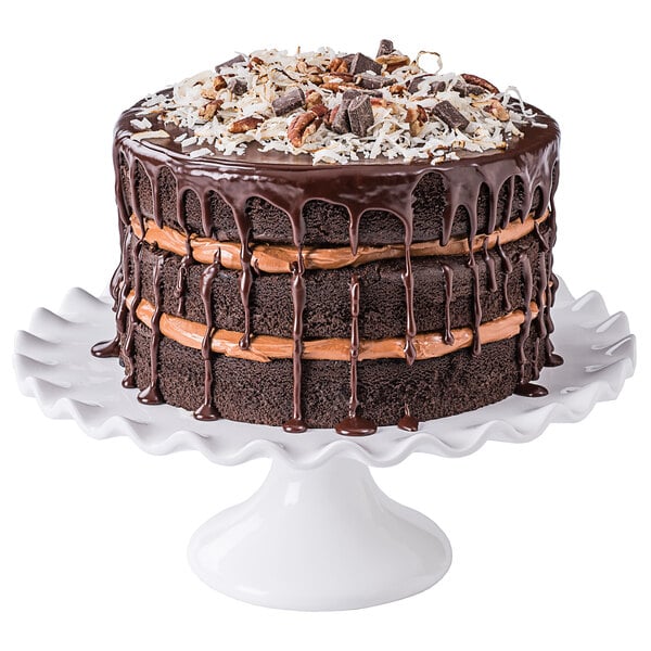A chocolate cake with Rich's Hershey's Chocolate icing and nuts on a white plate.