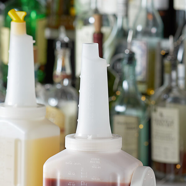 A white Vollrath pourer on a bottle of liquid.