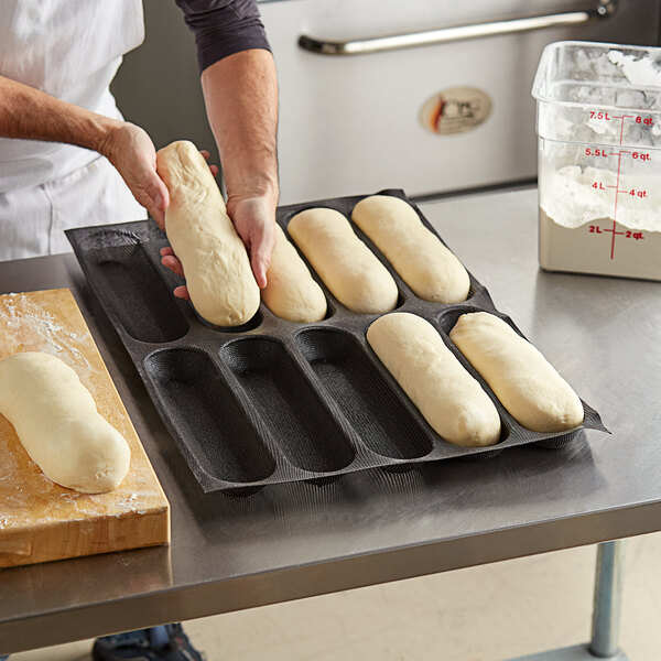 A person placing dough in a Sasa Demarle oblong bread mold.