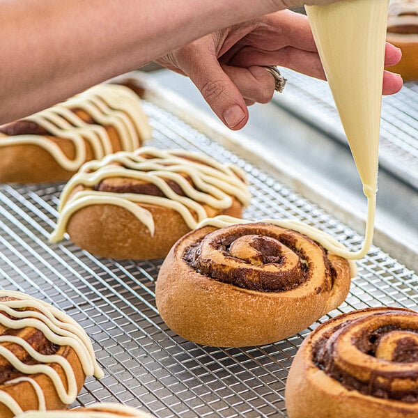 A person icing a fresh Rich's cinnamon roll.