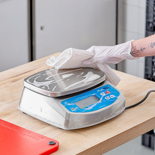 A digital portion control scale being cleaned with a cloth.