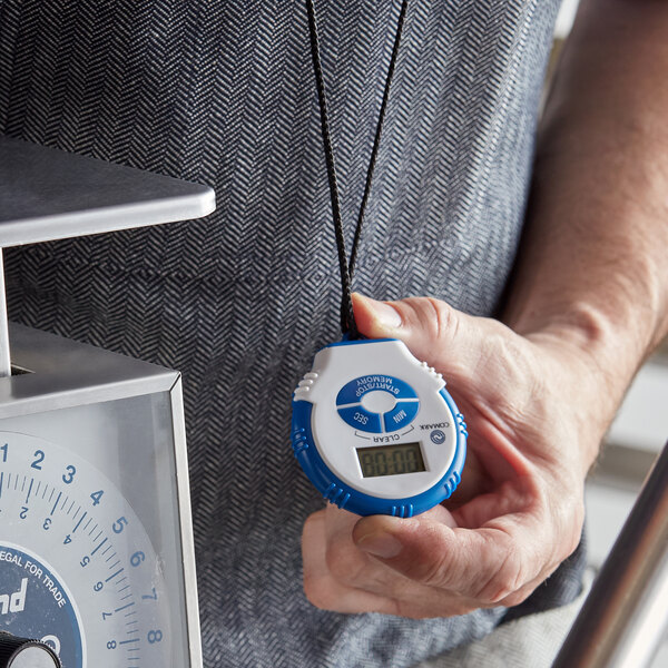 A person holding a Comark digital kitchen timer/stopwatch.