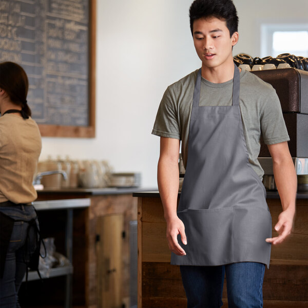 A man wearing a Choice gray bib apron over a white shirt.