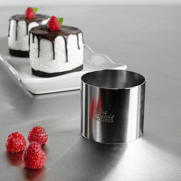 A cake made with a Fat Daddio's stainless steel round cake mold with a strawberry on top sitting on a plate with raspberries.