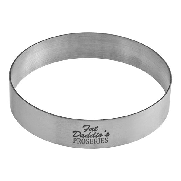 A circular stainless steel tart ring with a logo on it.