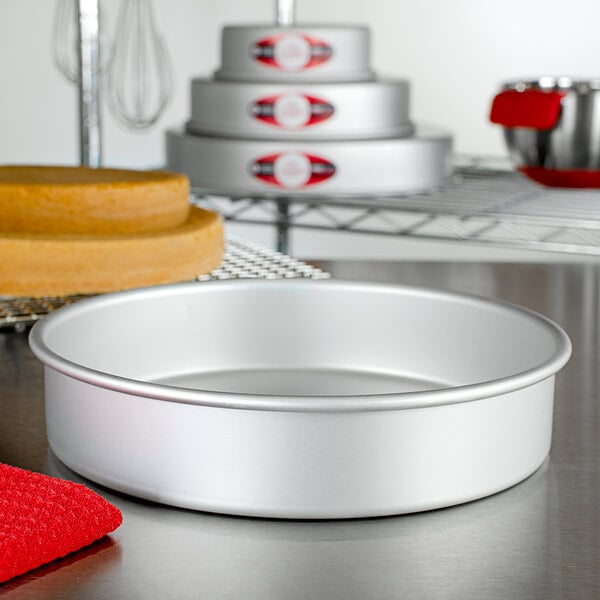 A round silver Fat Daddio's cake pan on a table.