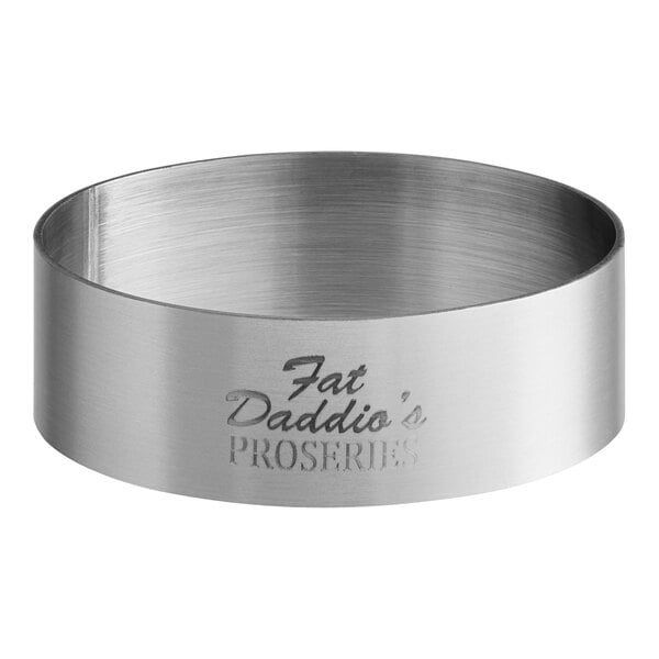 A silver circular stainless steel tartlet ring with text on it.