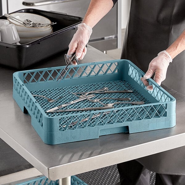 A person in black gloves holding a Noble Products combination flatware rack with utensils.