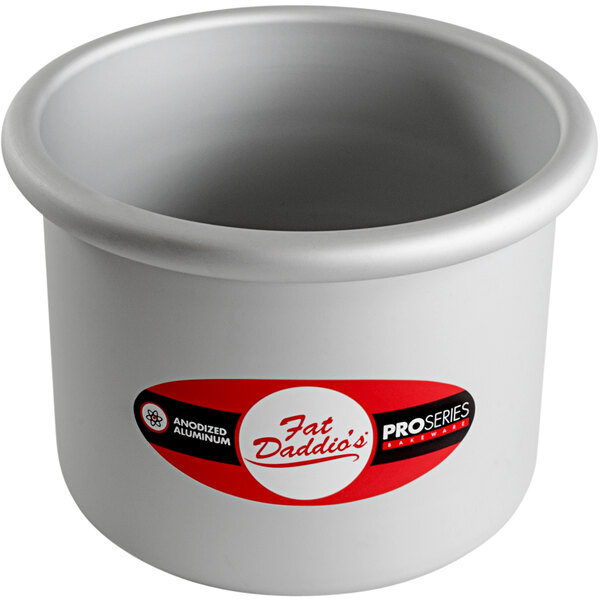 A Fat Daddio's round anodized aluminum cake pan on a counter in a professional kitchen.