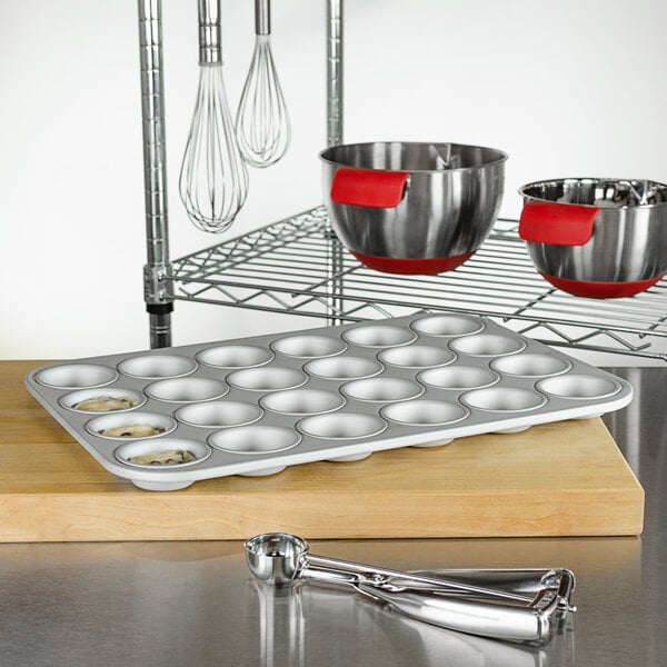 A Fat Daddio's mini muffin pan on a counter with utensils.