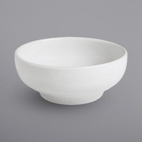 A Corona by GET Enterprises bright white porcelain footed bowl on a gray surface.