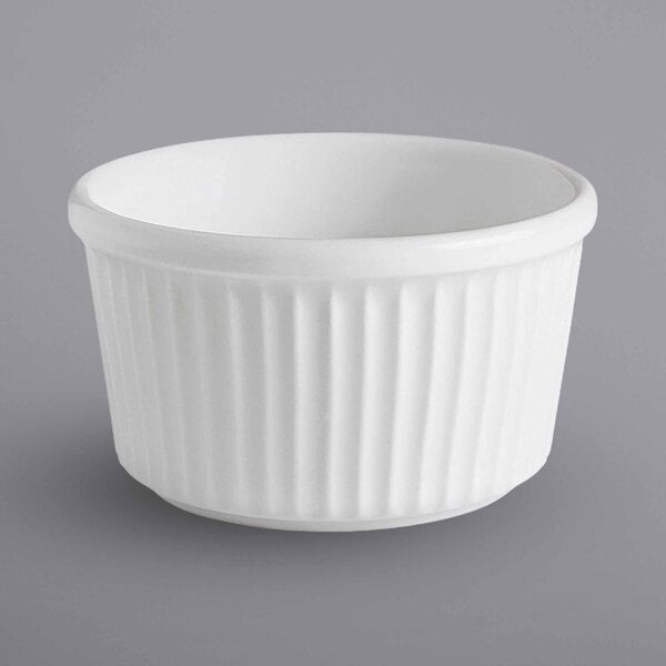 A close up of a white bowl with a ribbed rim on a gray surface.