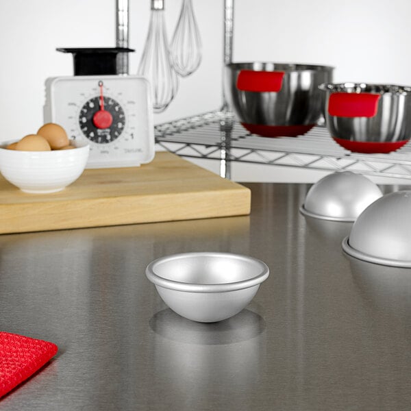 A Fat Daddio's hemisphere cake pan on a kitchen counter.