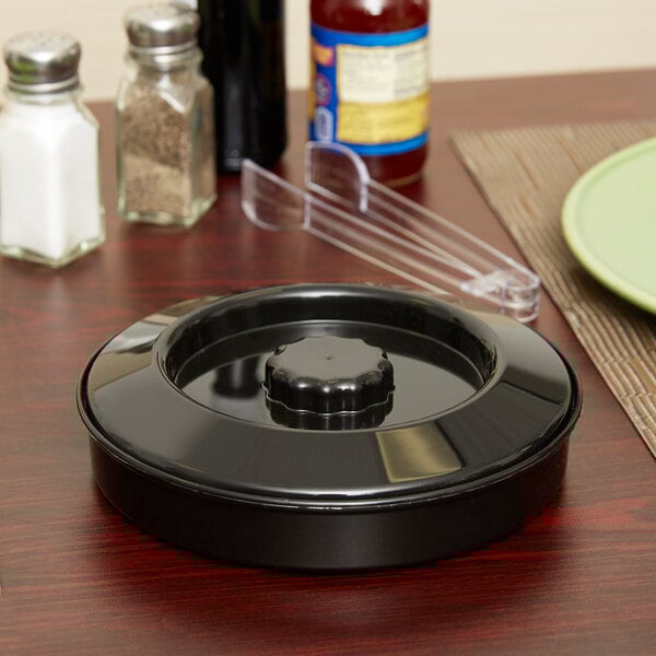 A black circular Carlisle polypropylene container with a black interlock lid on a table.