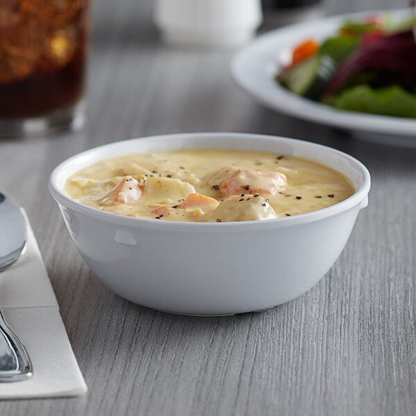 An Acopa Foundations white melamine bowl of soup on a table.