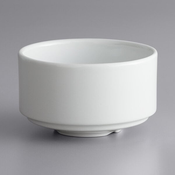 A stack of 24 bright white porcelain soup cups on a gray surface.