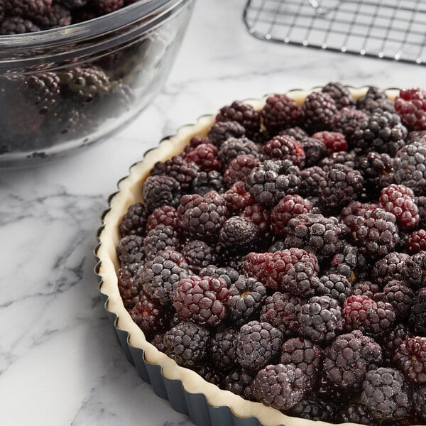 A bowl of 30 lb. IQF whole blackberries on a marble surface.