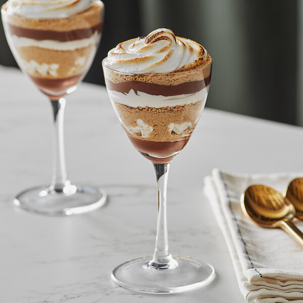 Two Acopa Nick and Nora glasses filled with dessert on a table.