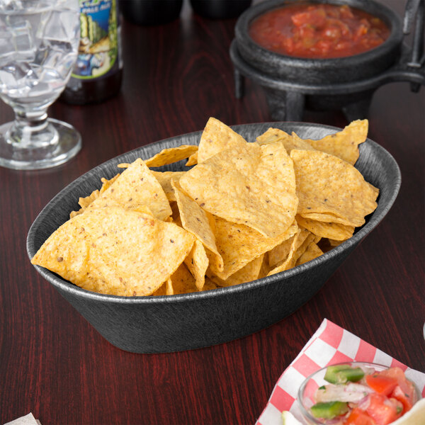 A large oval basket filled with tortilla chips on a table in a Mexican restaurant.