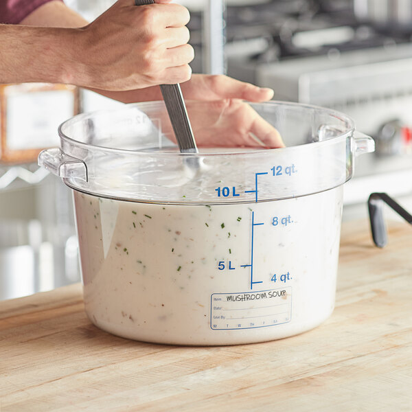 A person mixing food in a large clear container.