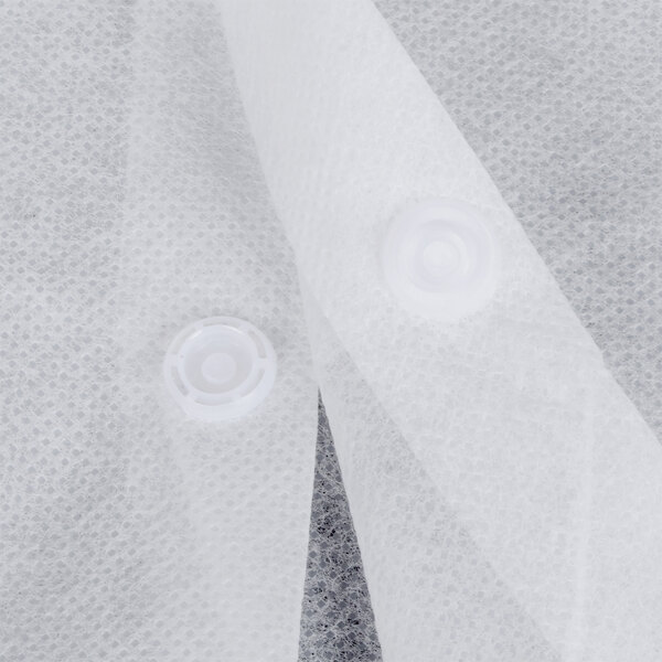 A close up of a white disposable lab coat with buttons.