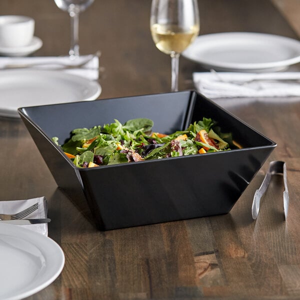 An Acopa Rittenhouse black square melamine bowl filled with salad on a table.