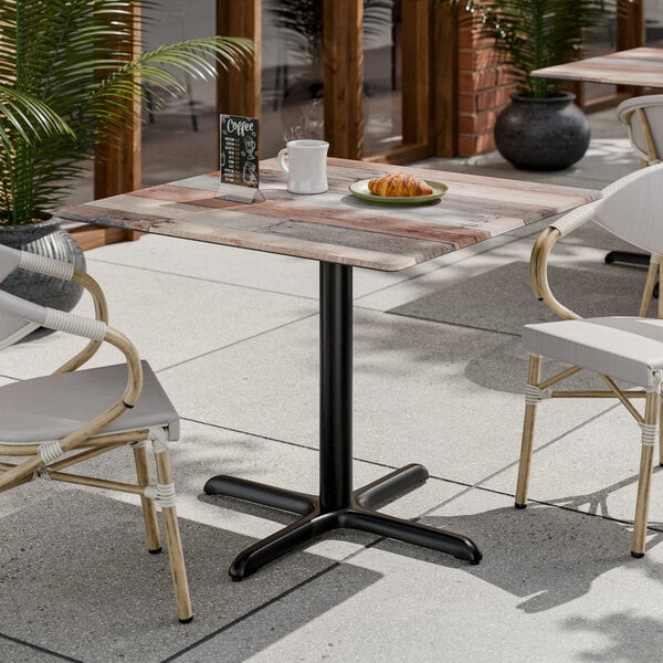 A square table with a textured mixed plank finish and a black pedestal base.