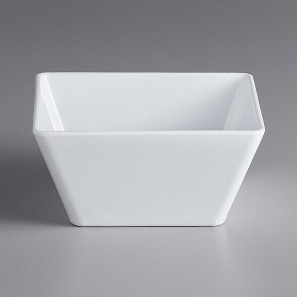 An Acopa Rittenhouse white square melamine bowl on a gray surface.