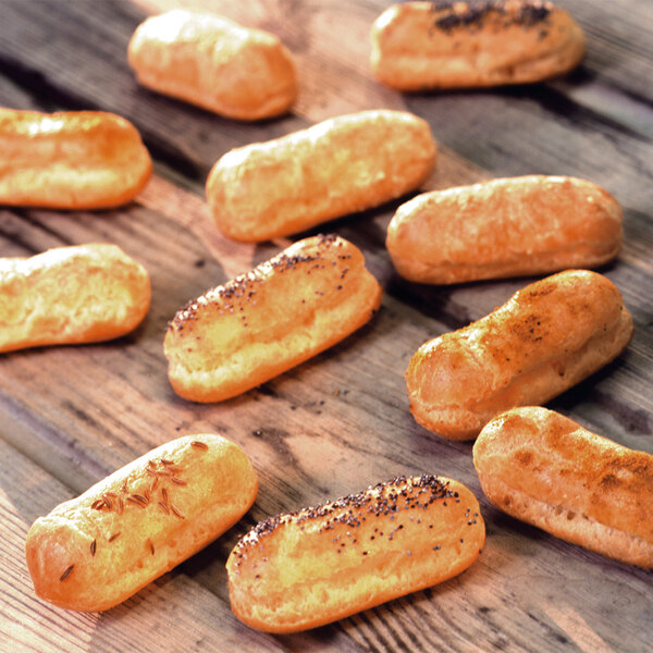 A close-up of a group of mini-eclairs on a wood surface.