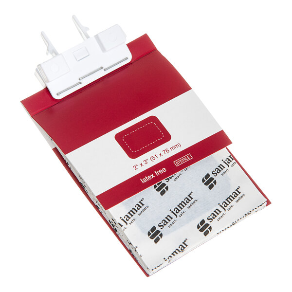 A red and white bandage dispenser with individually wrapped bandages partially visible, labeled with 'san jamar' and size information.