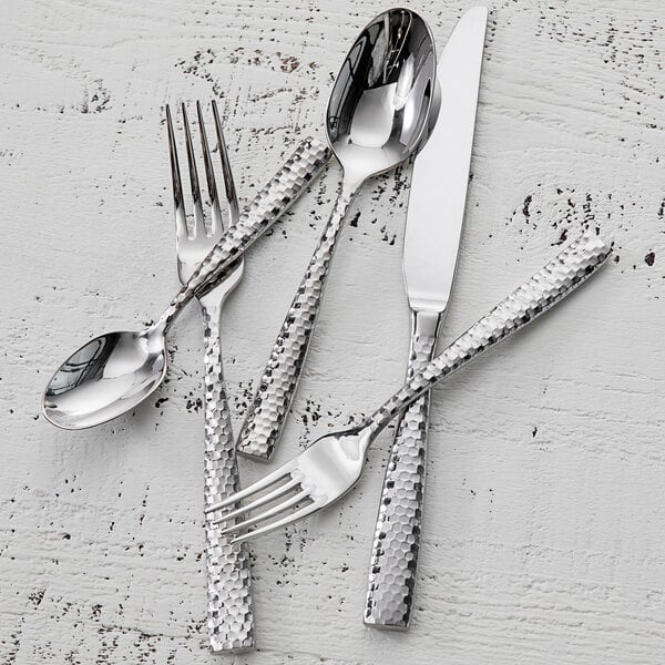 A close-up of a Fortessa Lucca stainless steel serving spoon with faceted details.