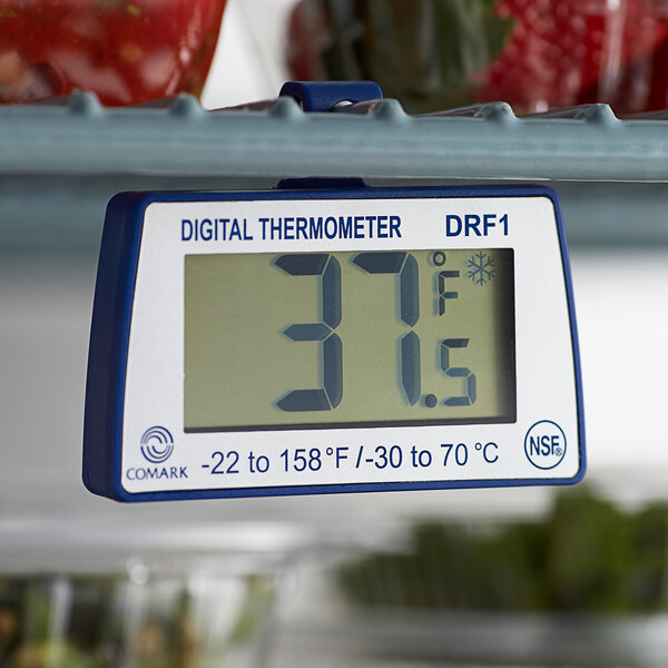 A Comark digital refrigerator/freezer thermometer on a shelf.