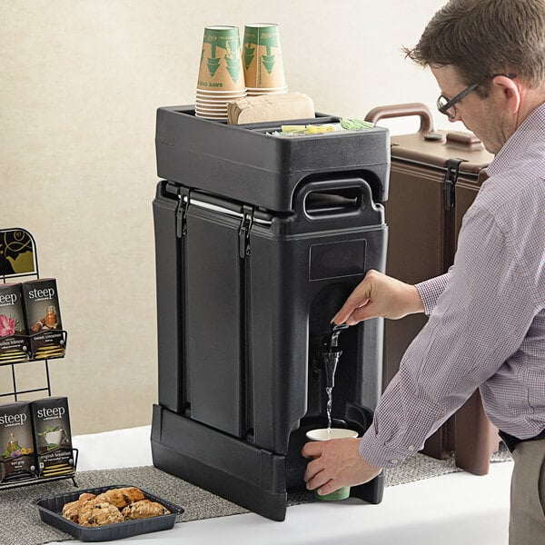 A man pouring a drink into a black Cambro insulated beverage dispenser.