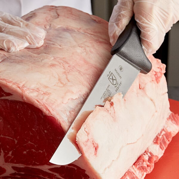 Butcher knife trimming fat off of large cut of meat