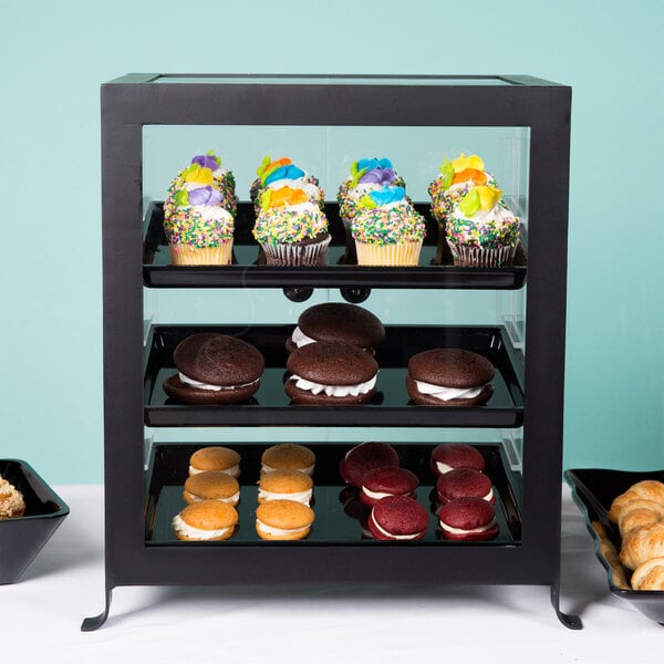 A black Cal-Mil Soho display case with cupcakes and cookies inside.