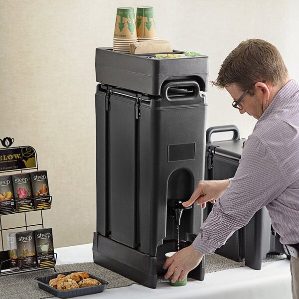 A man using a black Cambro insulated beverage dispenser to pour water.