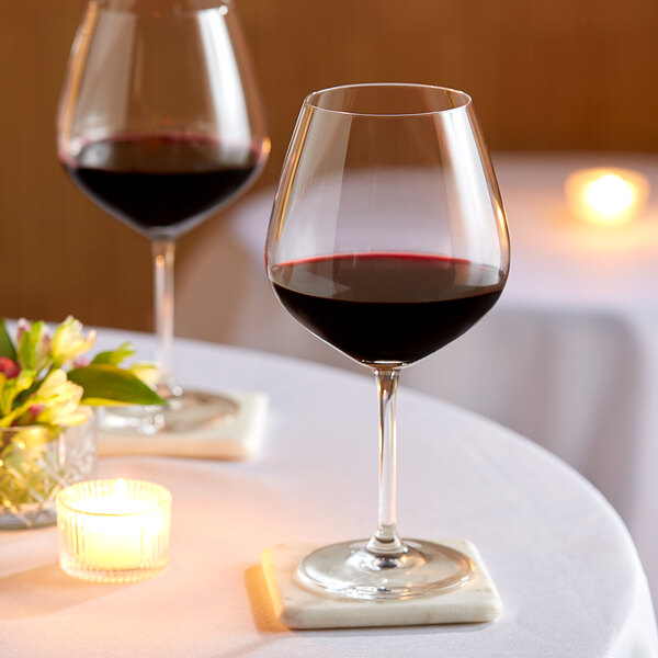 Two Schott Zwiesel Fortessa claret wine glasses of red wine on a table with candles