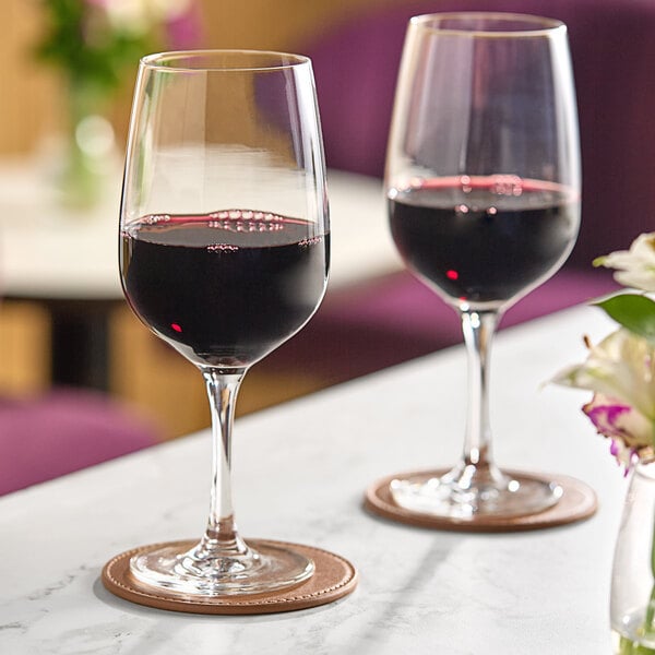 Two Schott Zwiesel red wine glasses filled with red wine on a table.