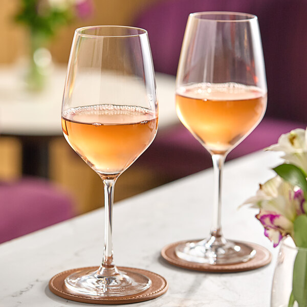 Two Schott Zwiesel red wine glasses on a table with flowers.