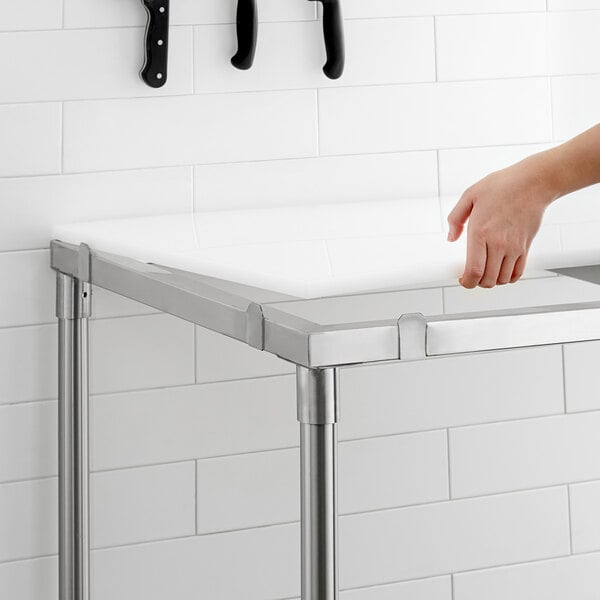 A hand using a knife on a Regency poly top table.