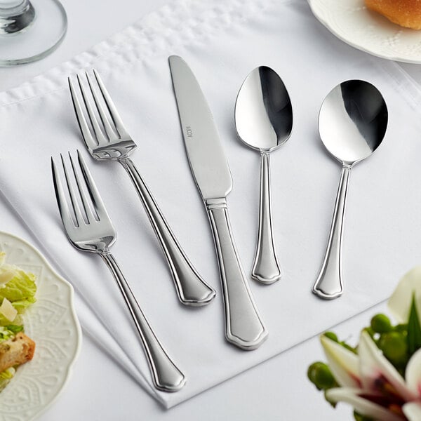 Acopa Sienna stainless steel fork and knife on a white tablecloth.