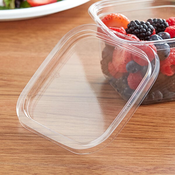 A Fabri-Kal plastic deli container lid filled with strawberries.