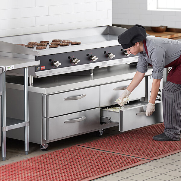 A woman in a commercial kitchen using a Beverage-Air 4 drawer refrigerated chef base.