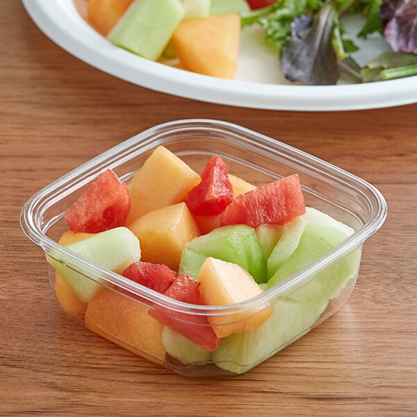 A close up of a square plastic container of fruit.