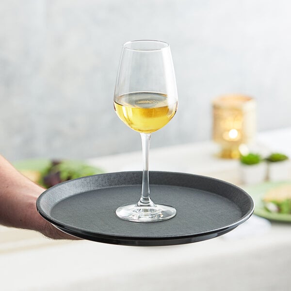 a hand holding a tray with a glass of wine