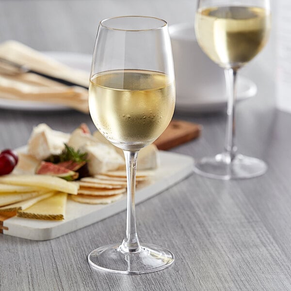 Two Anchor Hocking Vienna wine glasses next to a plate of cheese and grapes.