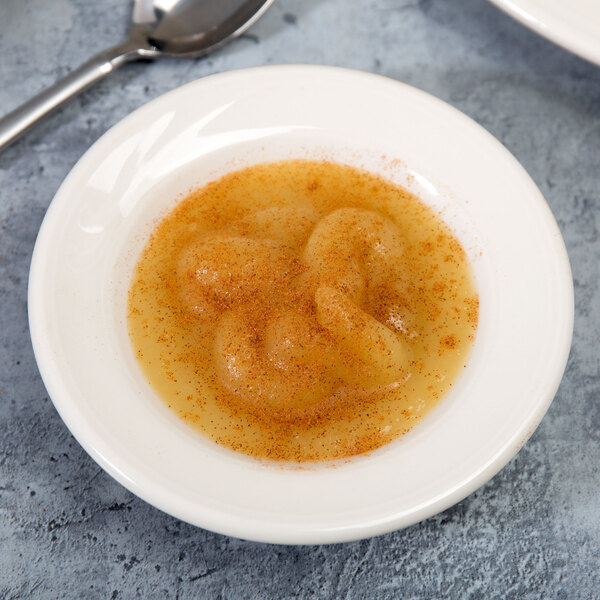 A Homer Laughlin ivory china monkey dish filled with food with a spoon.
